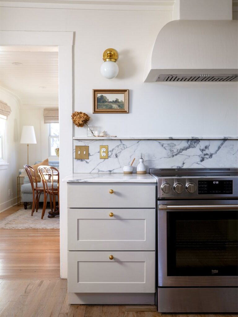 Curved white plaster hood over the range, veined quartz backsplash, doorway to living room