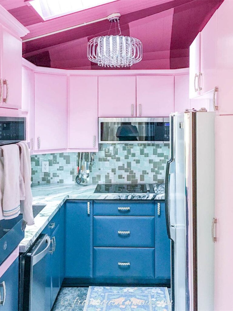 Small galley kitchen with light pink upper cabinets and dark teal lower cabinets