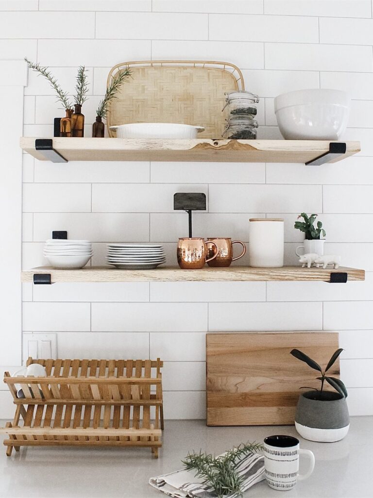 Close-up of two light wood open shelves on black brackets against white subway tile